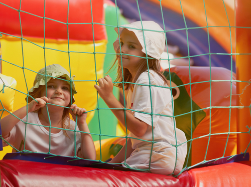 Cute,Little,Girls,Playing,In,Inflatable,Castle.,Two,Little,Sisters