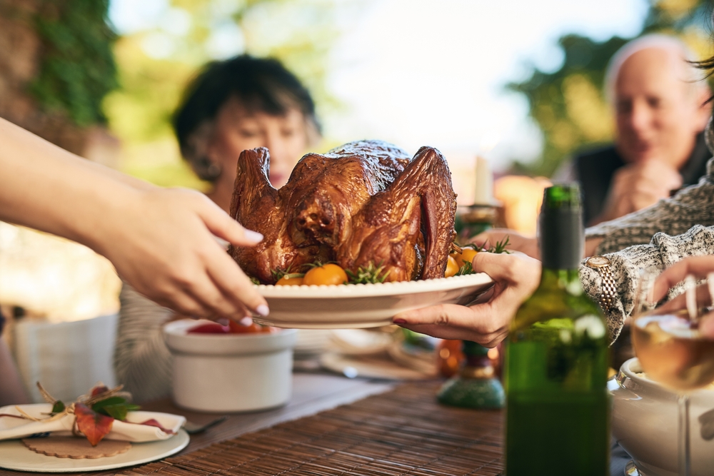 Thanksgiving,,Turkey,And,Hands,With,A,Family,Eating,A,Meal