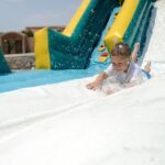 Splashdown!,Young,Boy,Sliding,Down,An,Inflatable,Water,Slide,Feet