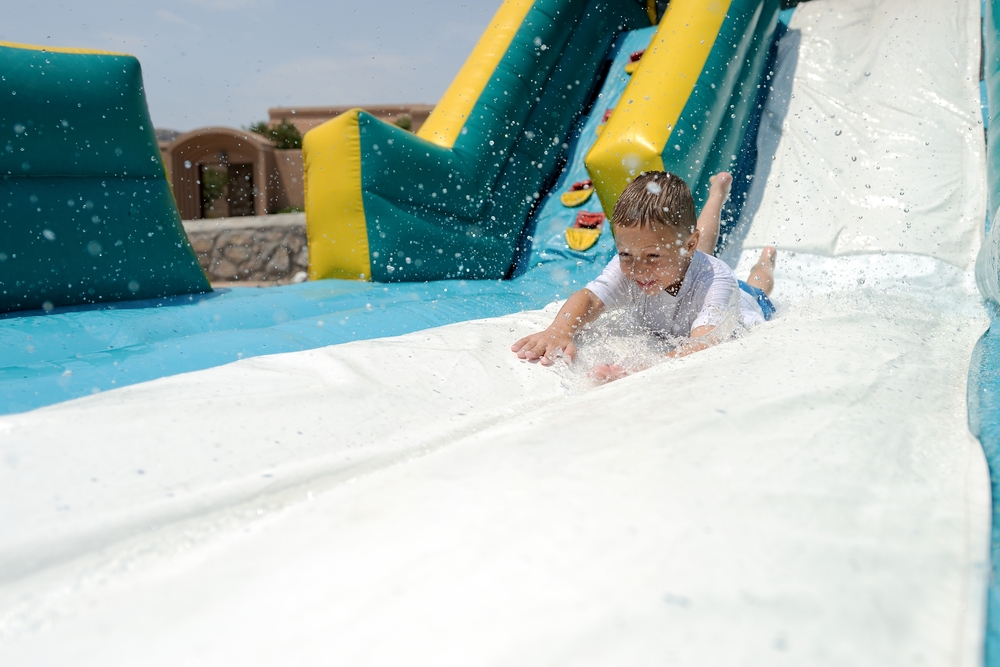 Splashdown!,Young,Boy,Sliding,Down,An,Inflatable,Water,Slide,Feet
